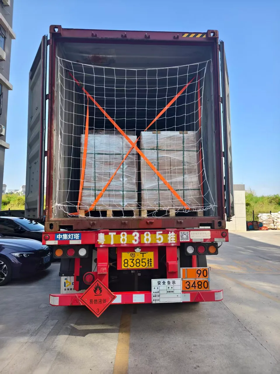 Wrapped pallets with orange securing straps and a white cargo net.