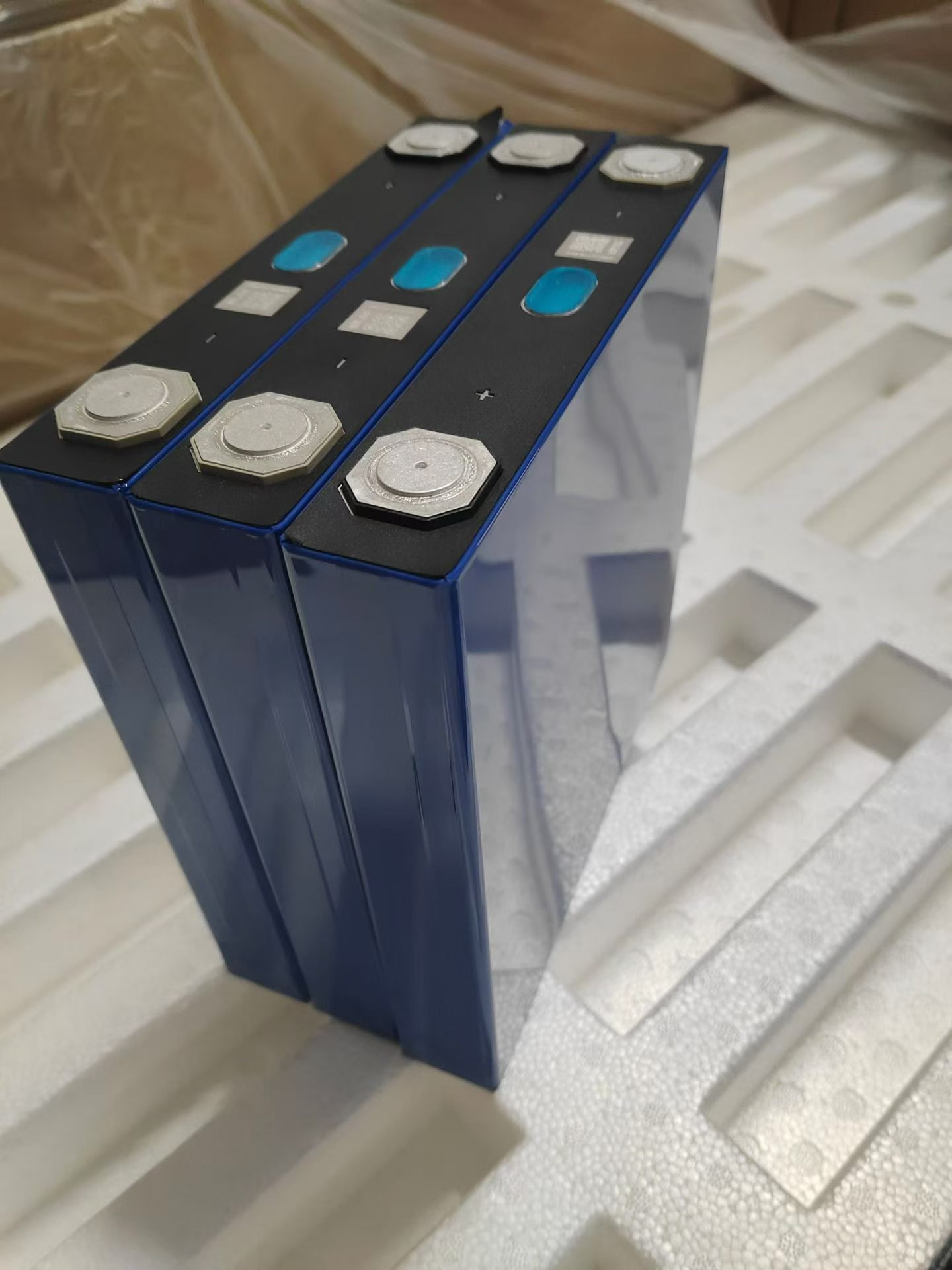 User-supplied photograph of three blue prismatic 150Ah cells in foam packing, with complete bodies and terminals visible.